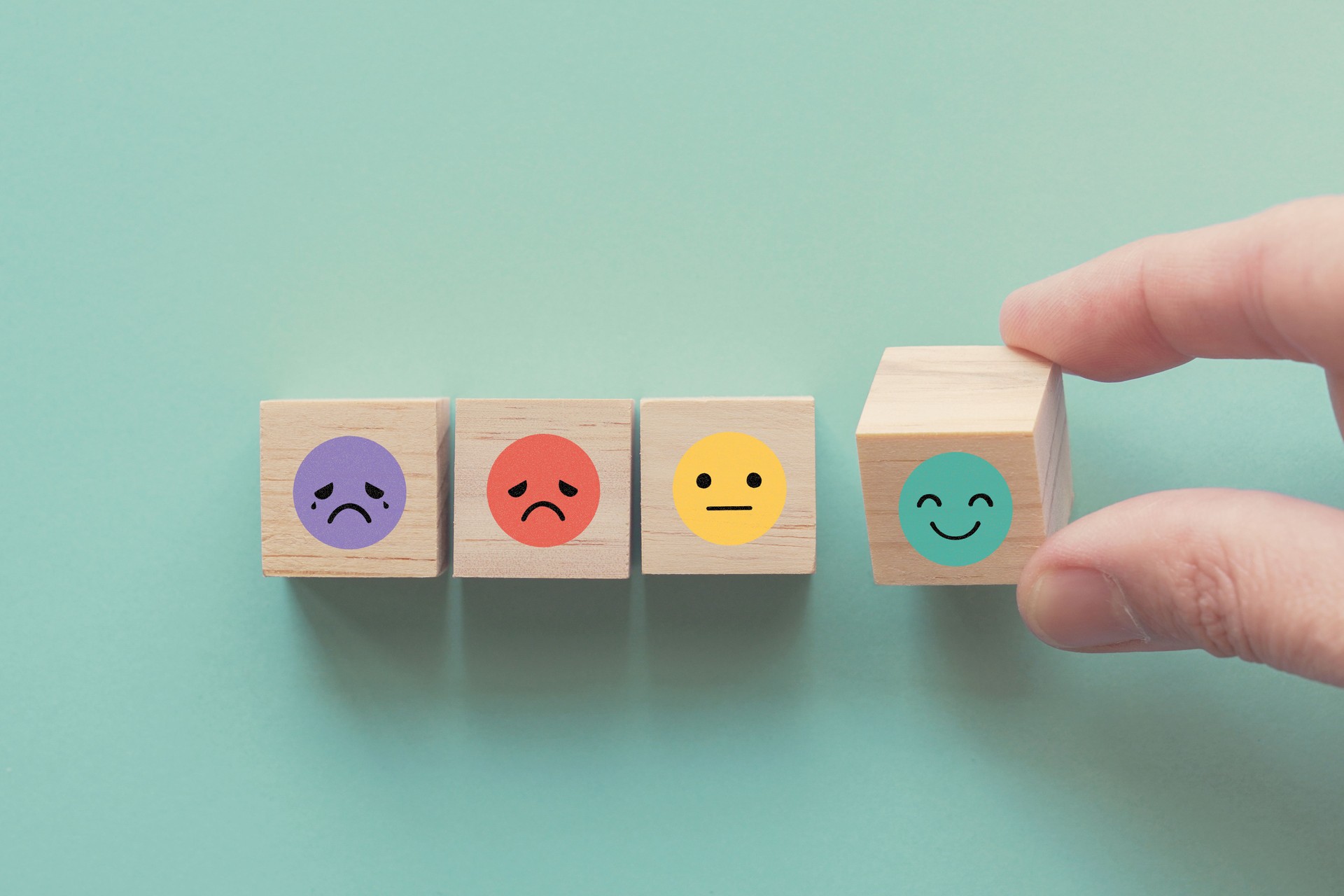 Hand choosing happy smile face wooden block, good feedback rating and positive customer review, mental health assessment, child wellness,world mental health day, think positive, compliment day concept